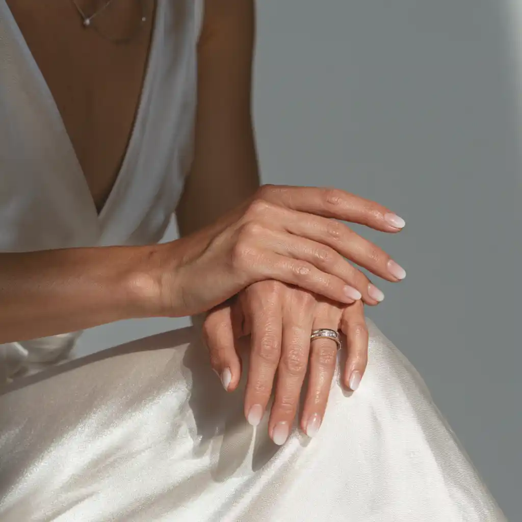 Mains délicates sur une robe satinée.